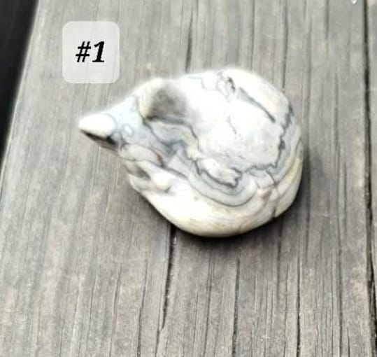 Small sculptures of sleeping cats, made from various natural stones.