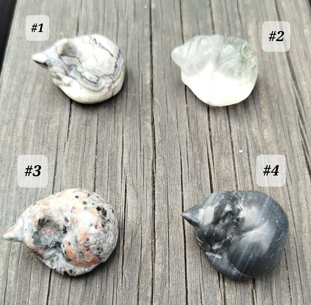 Small sculptures of sleeping cats, made from various natural stones.