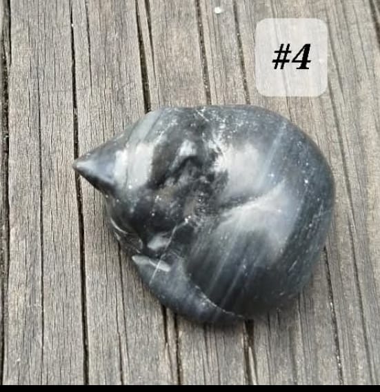 Small sculptures of sleeping cats, made from various natural stones.